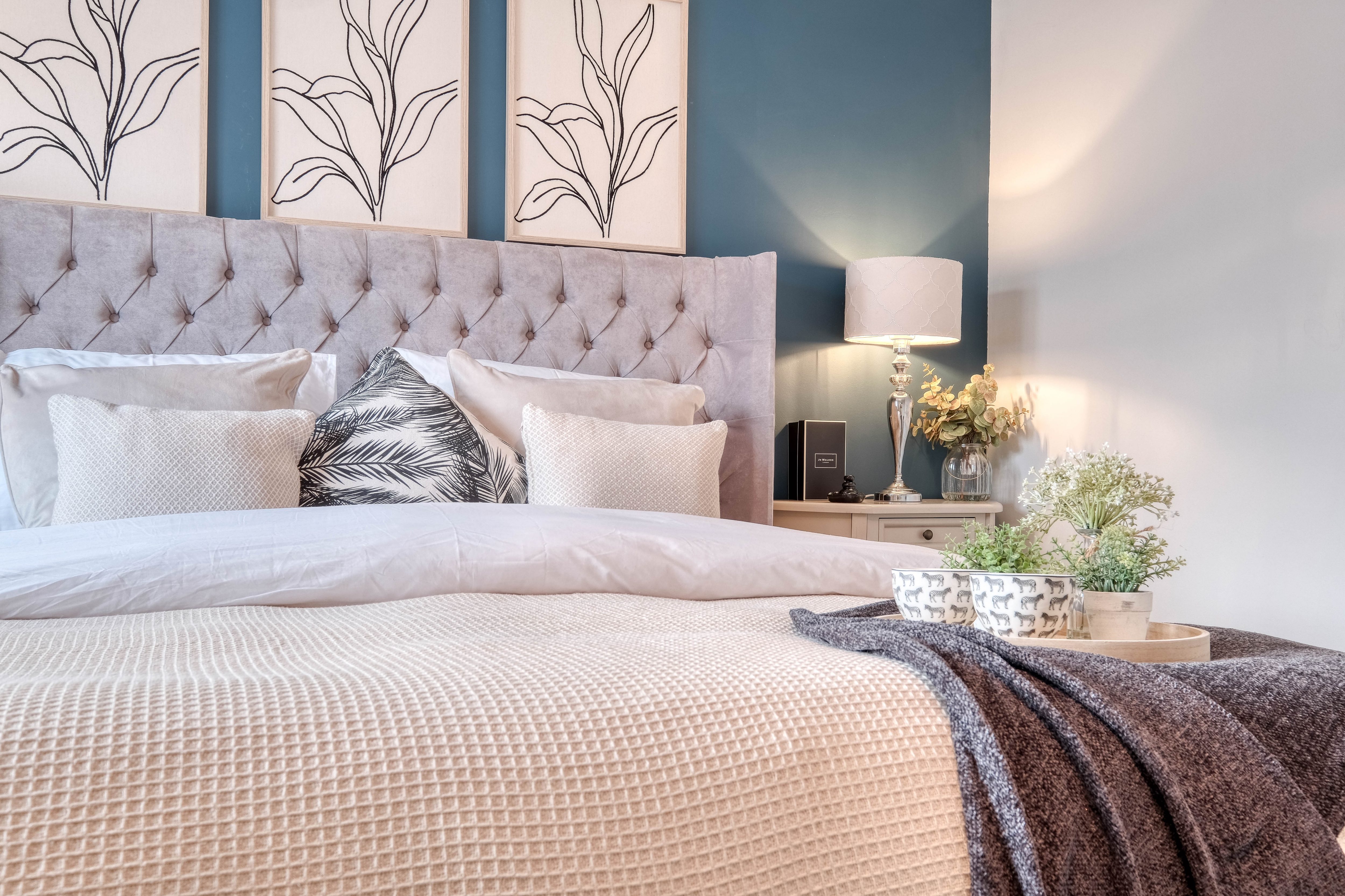 Home staging bedroom with button upholstered bed with pillows, blankets and throws
