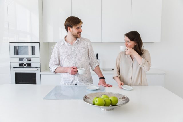 Man and woman, couple in the kitchen with a drink discussing property surveys