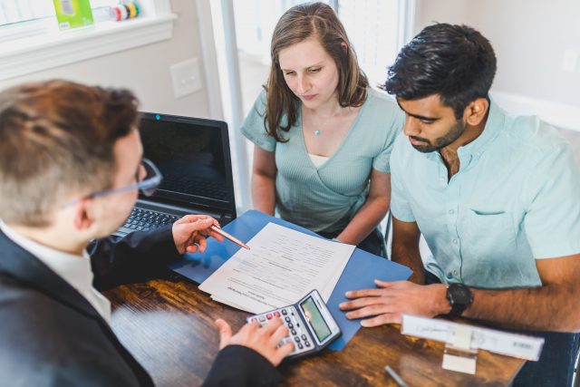 couple at a desk with mortgage advisor applying for mortgage